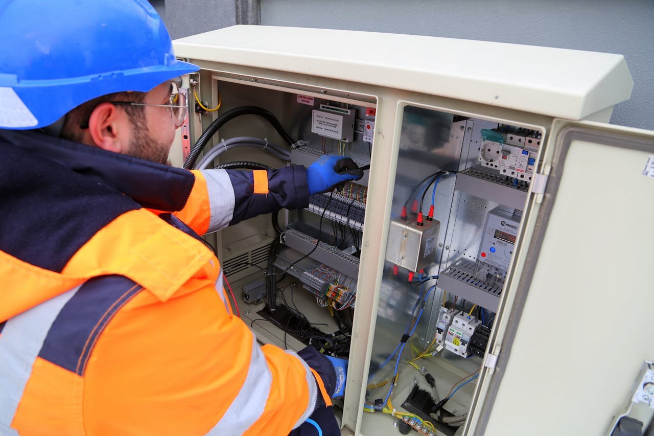 about-01 Engineer in safety gear working on an outdoor electrical panel, ensuring system functionality.