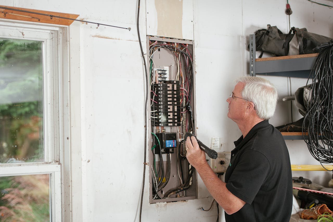 gallery-5 An electrician carefully examines a residential fuse box indoors, ensuring electrical safety and compliance.